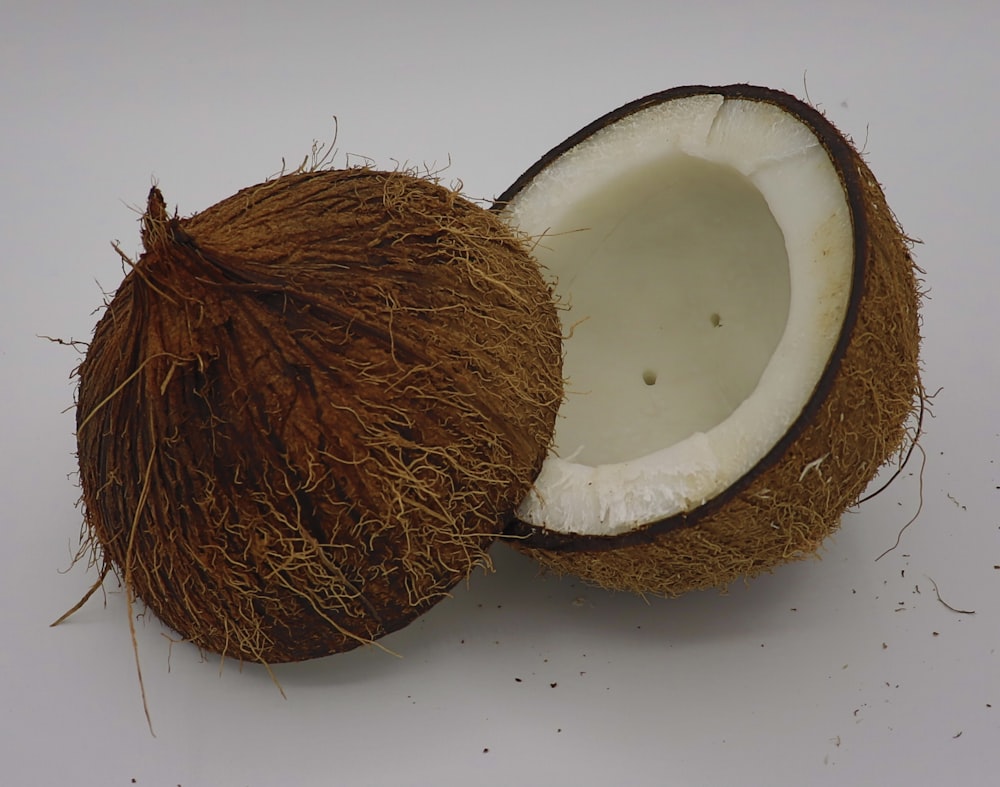 una noce di cocco mezza mangiata seduta sopra un tavolo bianco