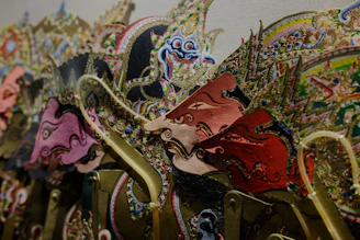 Close-up of hands crafting a colorful wayang kulit puppet with intricate details.