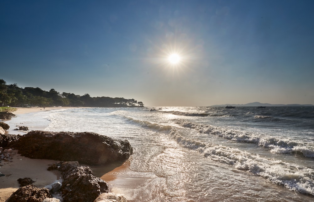 the sun is shining over the water at the beach