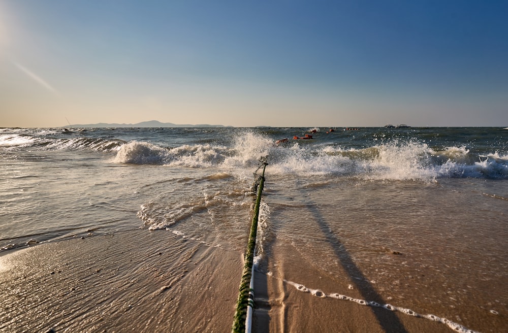 a fishing rod sticking out of the water on a beach