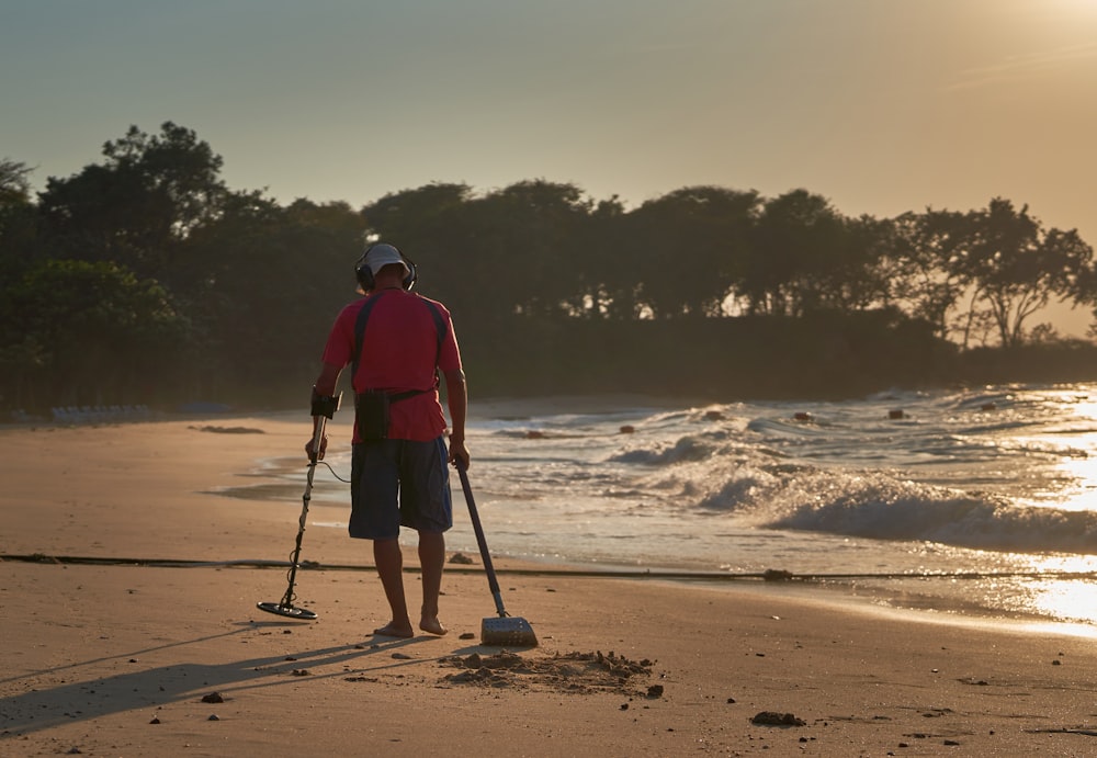 Un hombre parado en una playa sosteniendo un poste