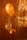 Three balloons, primarily in shades of gold and orange, are positioned against a backdrop of metallic tinsel. The lighting casts shadows on the balloons, enhancing their shiny and festive appearance.