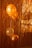 Three balloons, primarily in shades of gold and orange, are positioned against a backdrop of metallic tinsel. The lighting casts shadows on the balloons, enhancing their shiny and festive appearance.