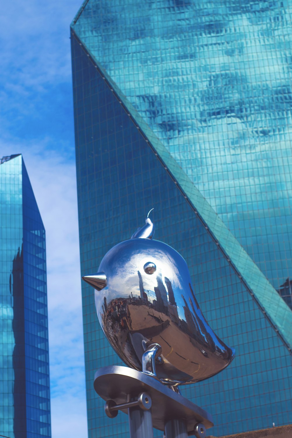 Una escultura de metal de un pájaro en un poste frente a un edificio