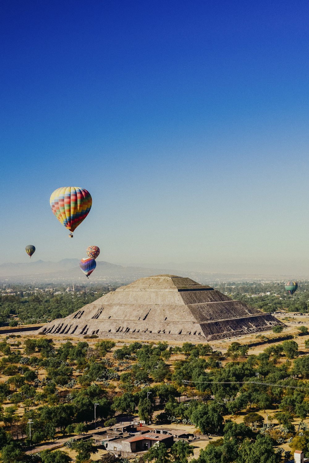 a group of hot air balloons flying over a pyramid