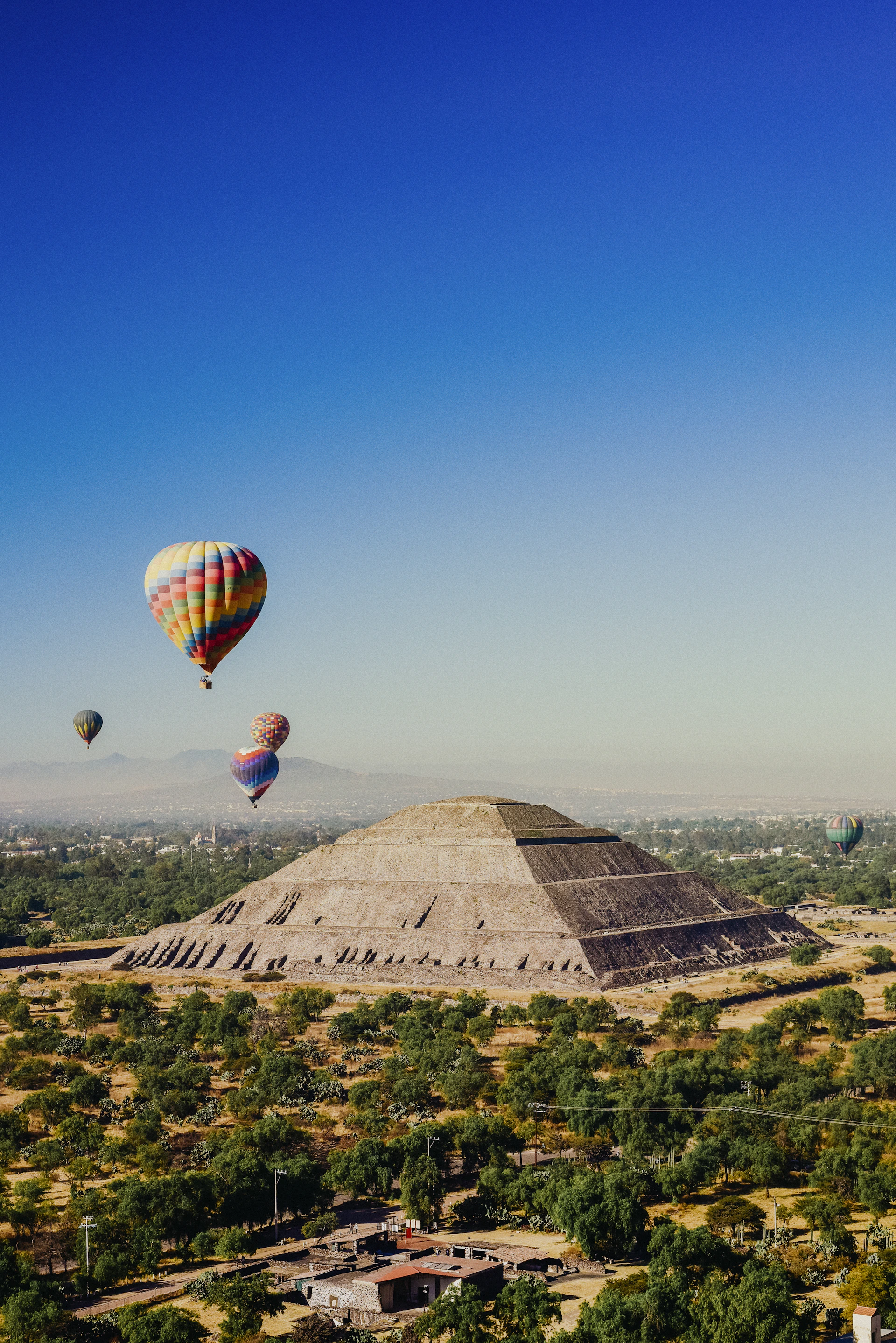 a group of hot air balloons flying over a pyramid