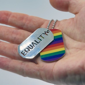 a person holding a rainbow dog tag in their hand