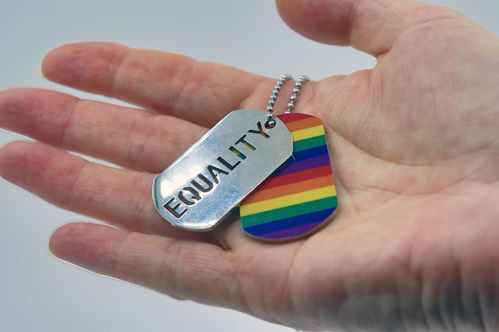 Una persona sosteniendo una placa de identificación arcoíris en la mano