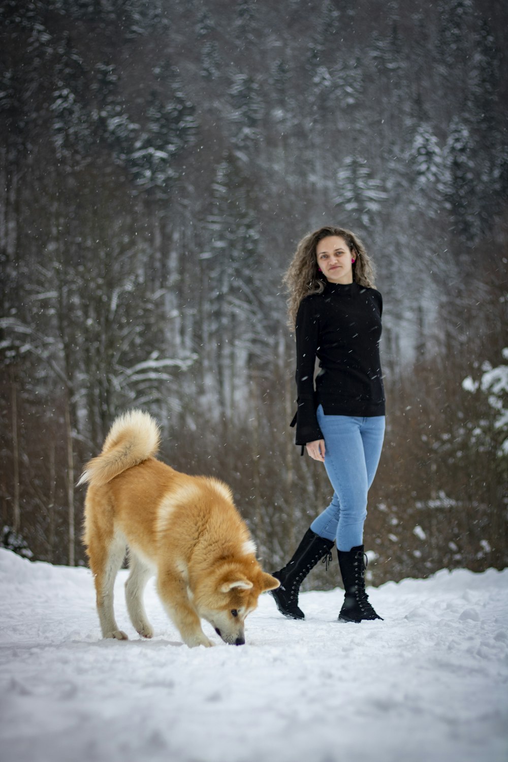 a woman is walking her dog in the snow