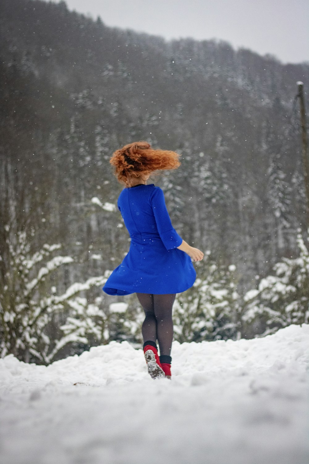 a woman in a blue dress is running through the snow