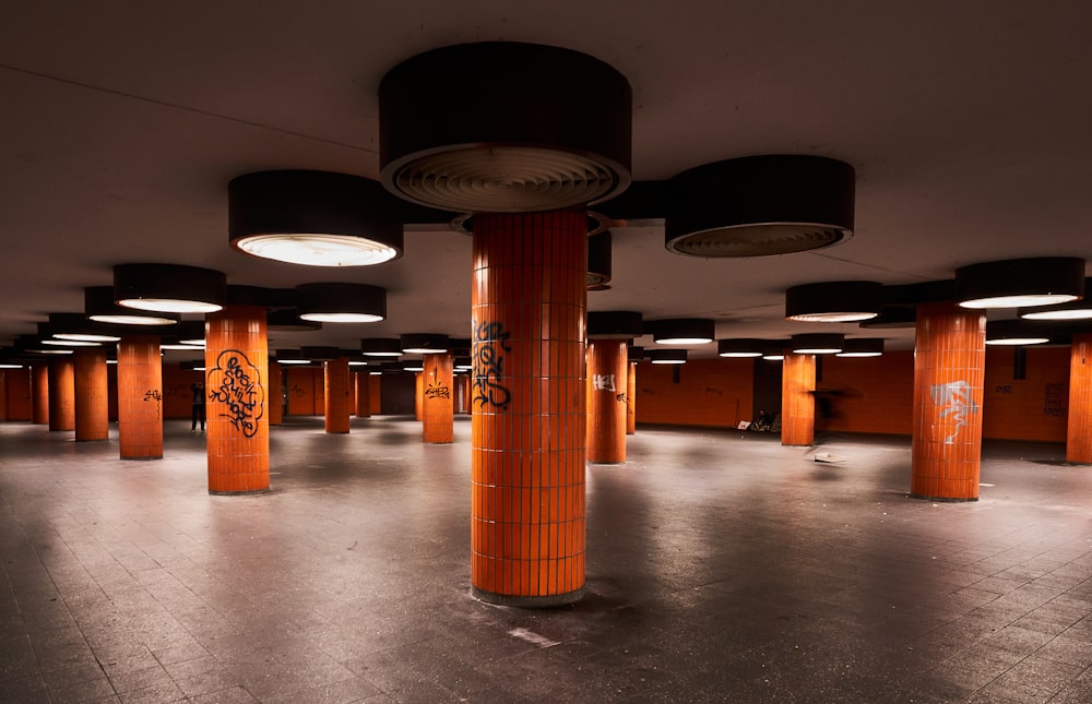 a large room with orange columns and graffiti on the walls