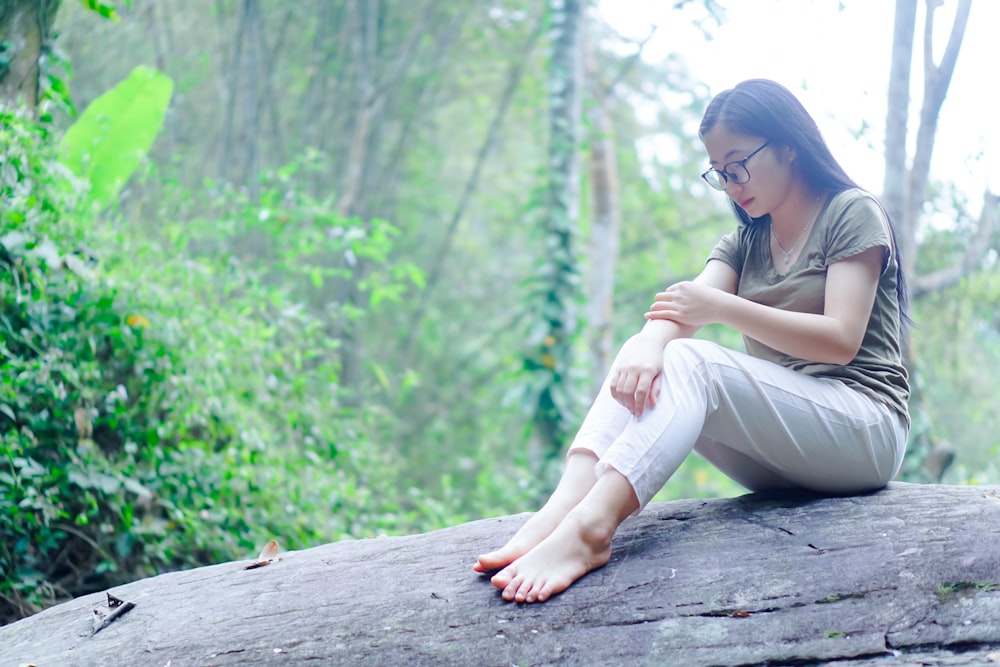 uma mulher sentada em uma rocha na floresta