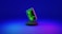 A smartphone displaying green computer code stands upright on a round, dark platform. The background fades from deep blue at the top to purple at the bottom, creating a futuristic and digital ambiance.