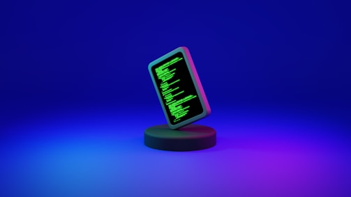 A smartphone displaying green computer code stands upright on a round, dark platform. The background fades from deep blue at the top to purple at the bottom, creating a futuristic and digital ambiance.