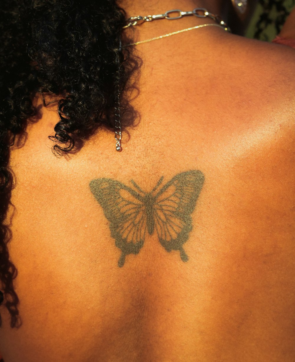 a woman with a butterfly tattoo on her back