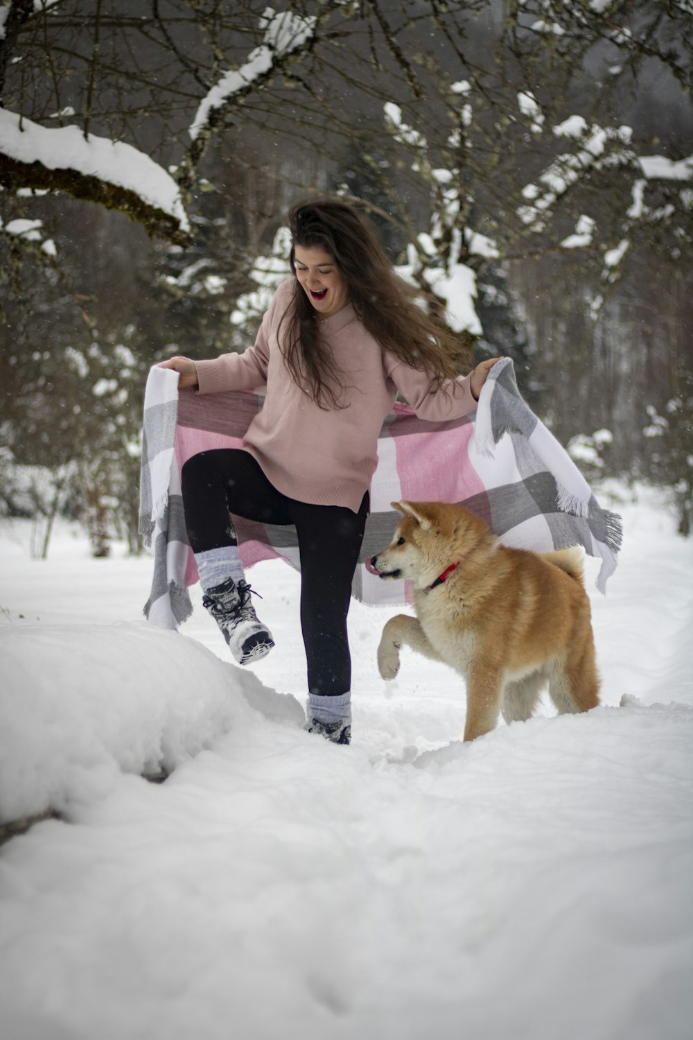 a woman is playing with her dog in the snow
