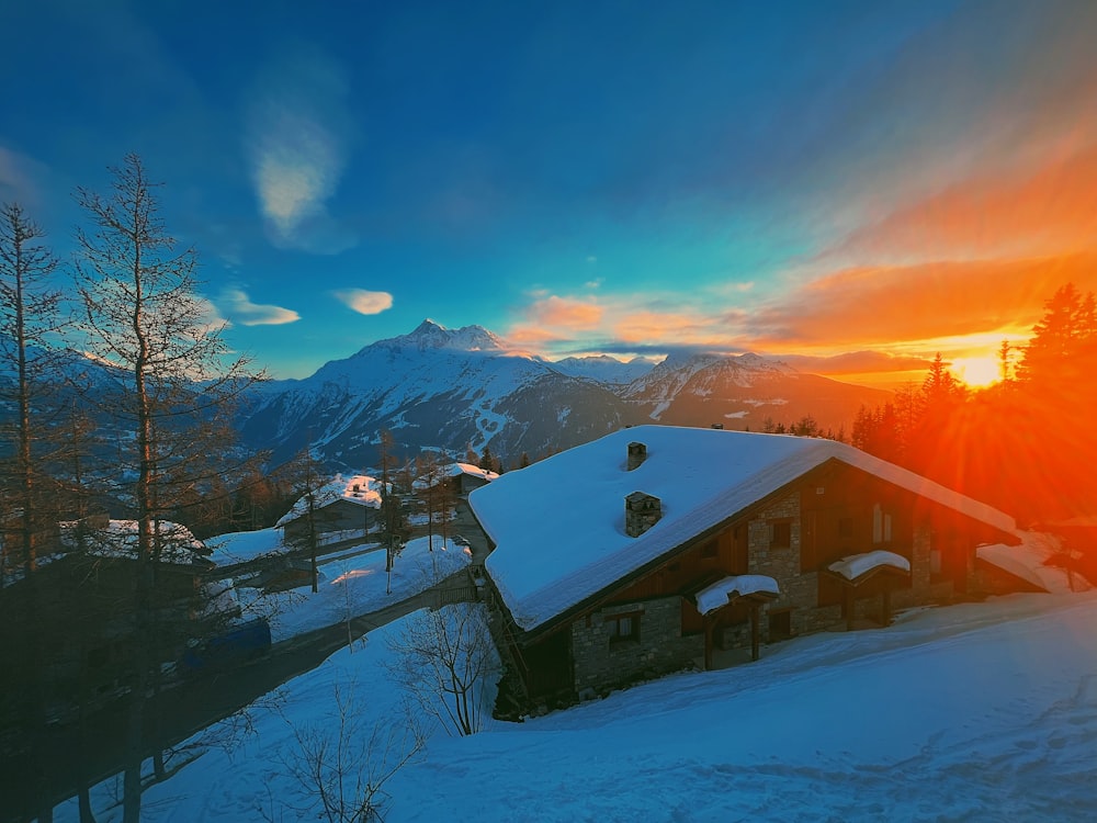 the sun is setting over a snowy mountain