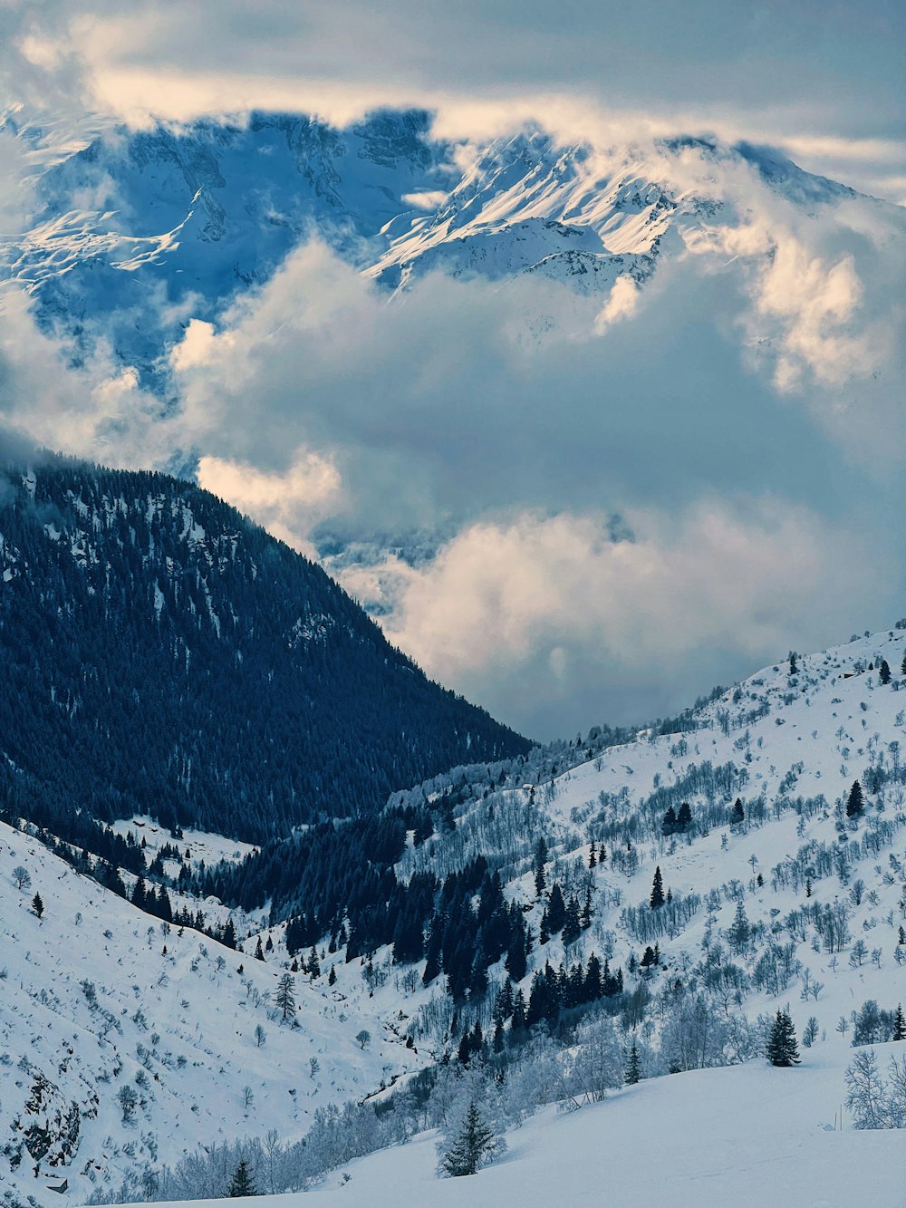 a mountain covered in snow with clouds in the background