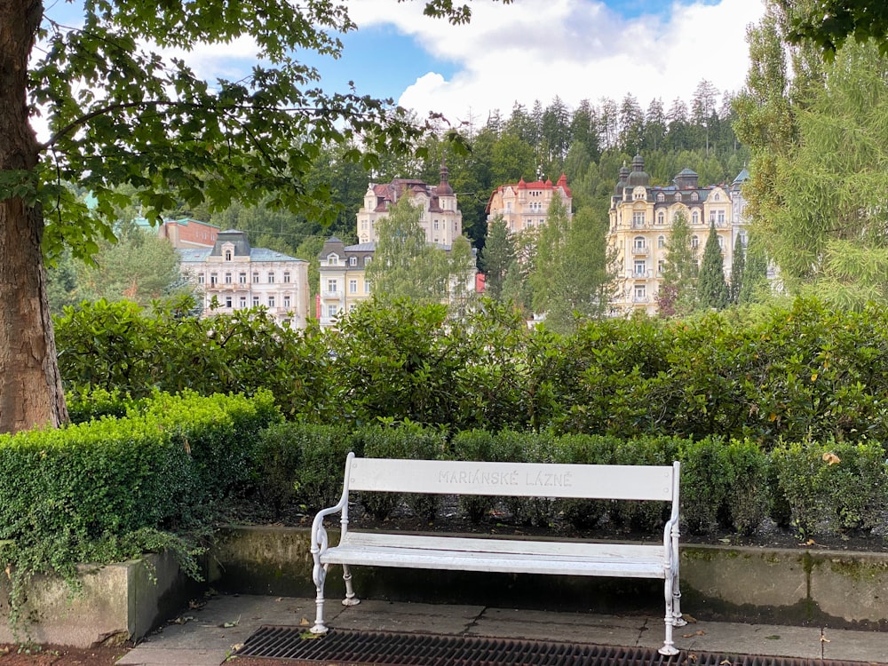 a white park bench sitting next to a lush green park