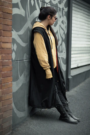 A trendy young man in a sleek urban outfit standing near a graffiti wall, showcasing casual men's fashion.