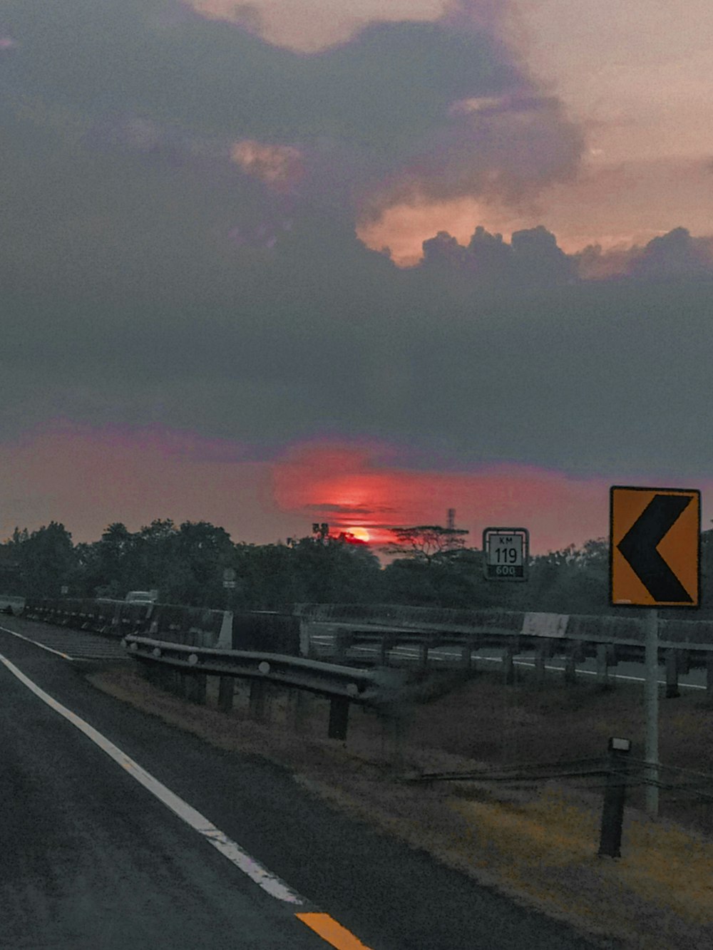 the sun is setting on the horizon of a highway
