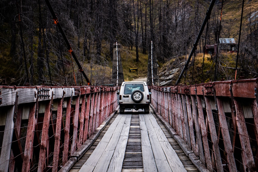 a car driving across a wooden bridge in the woods
