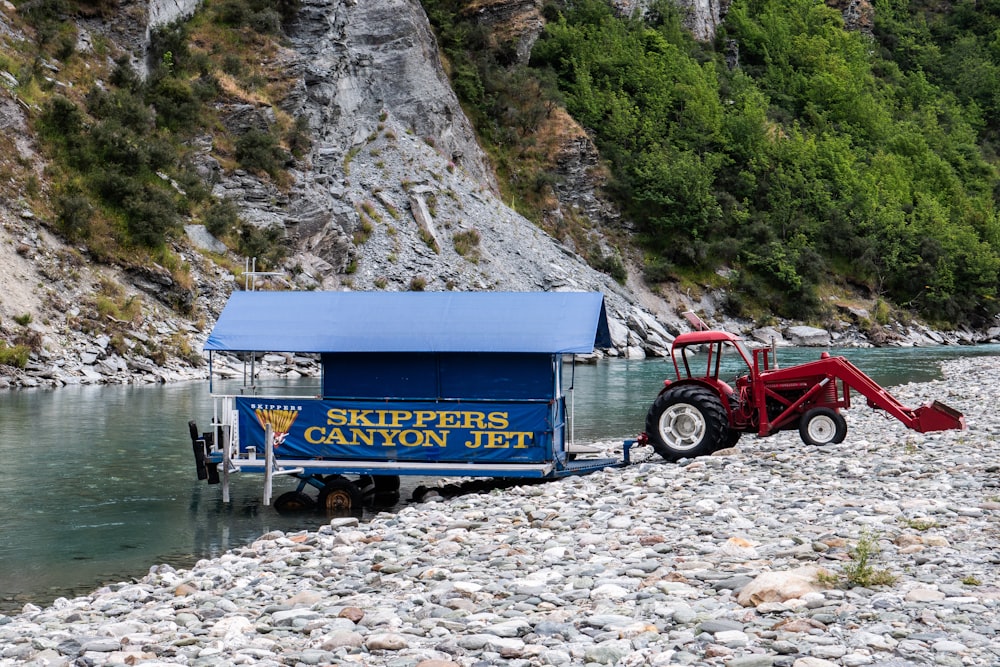 a tractor parked next to a trailer on a rocky shore