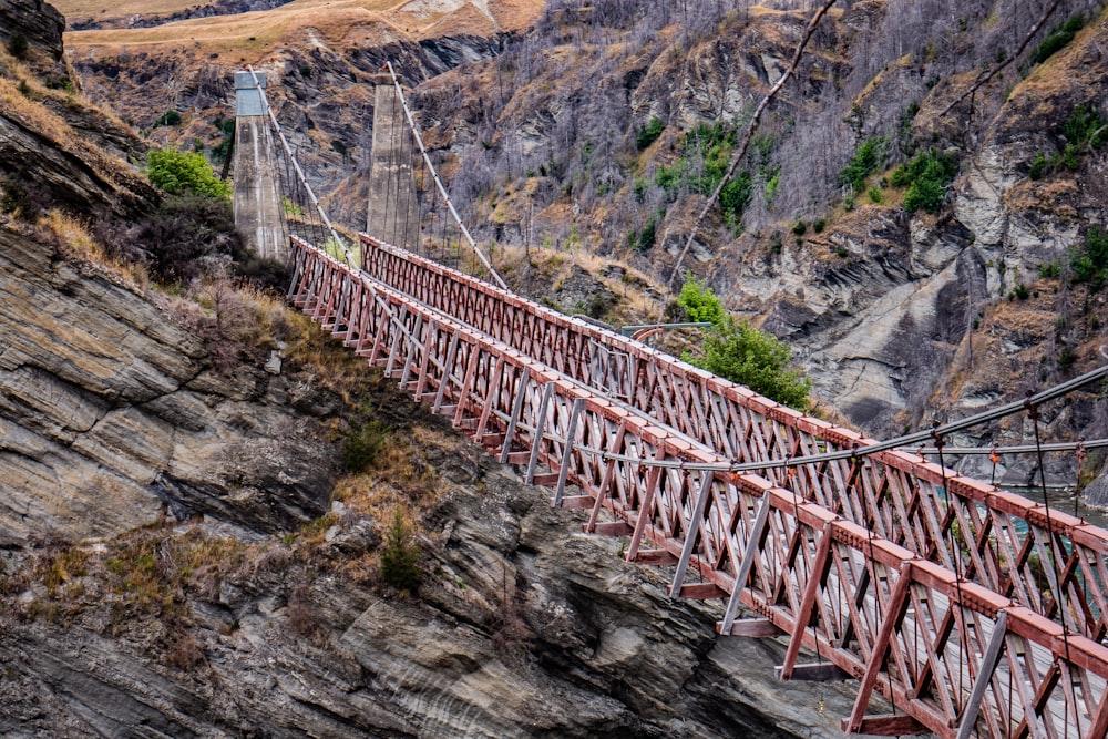 a red bridge going over a canyon with a mountain in the background