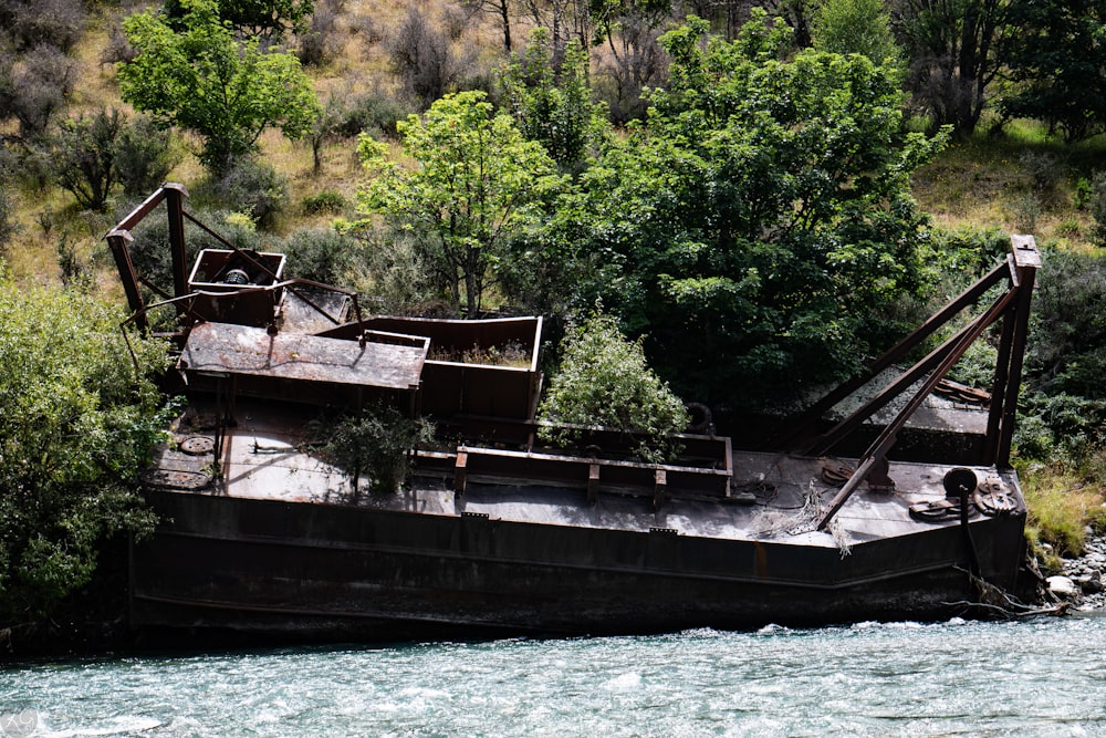 an old rusty boat sitting on the side of a river