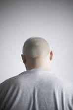 a man with a bald head standing in front of a white wall