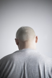 a man with a bald head standing in front of a white wall