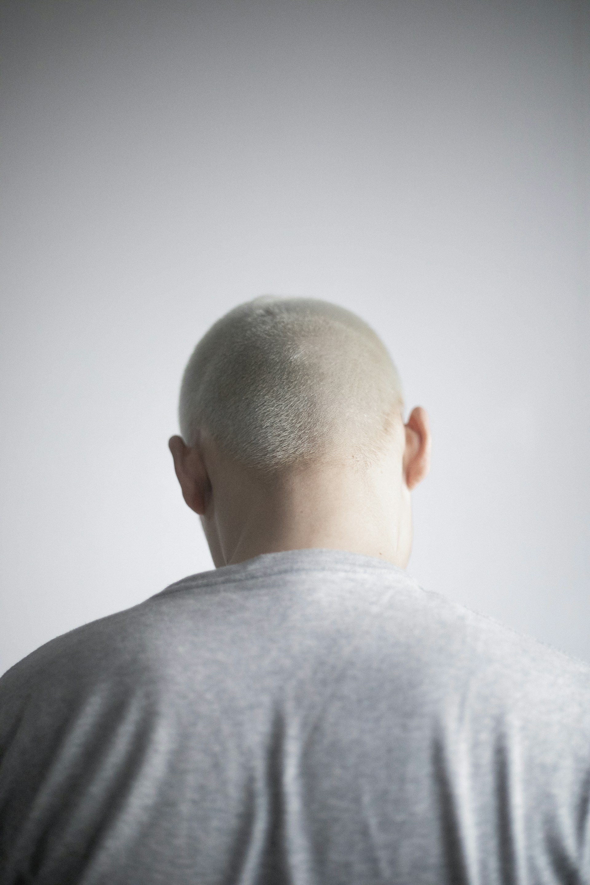 a man with a bald head standing in front of a white wall