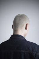 a man with a shaved head and a denim jacket