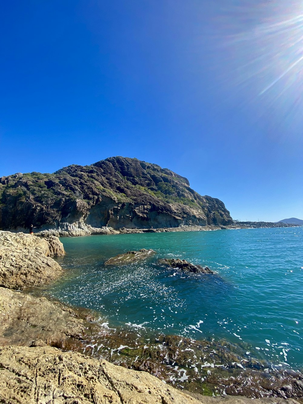 the sun shines brightly over a rocky beach