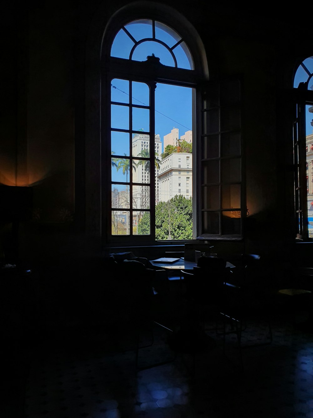 a dark room with two large windows and a view of a building