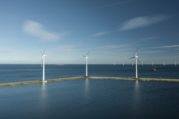 a row of wind turbines next to a body of water