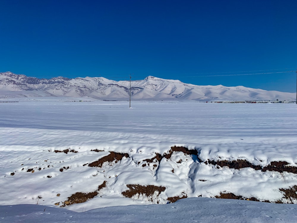 a snow covered field with mountains in the background