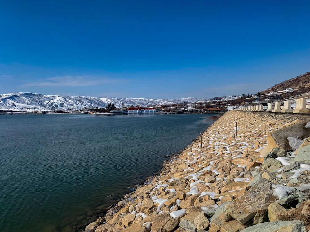 a body of water surrounded by rocks and snow covered mountains