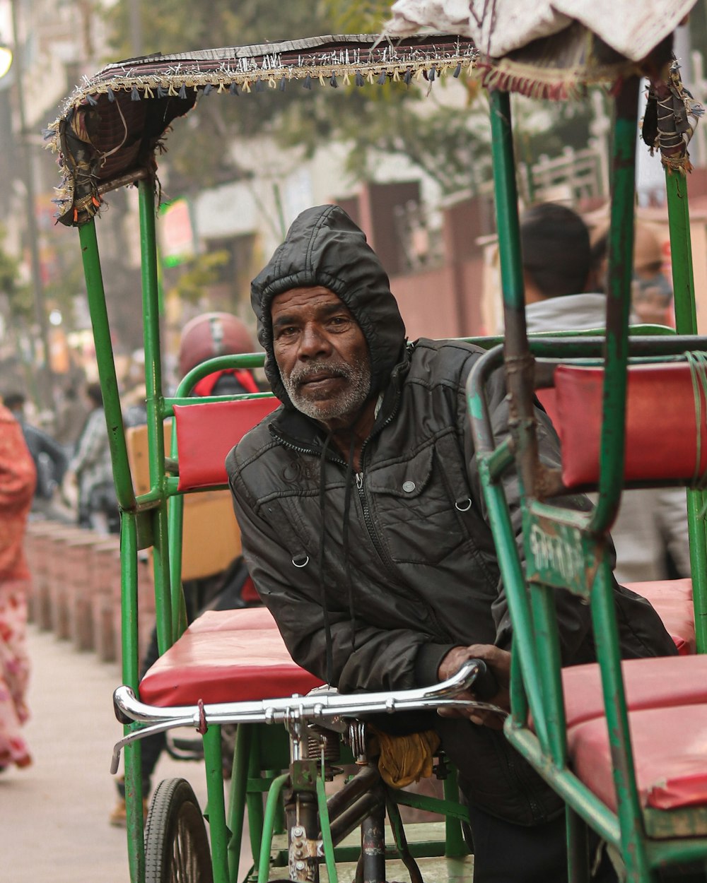 a man in a black jacket is riding a rickshaw