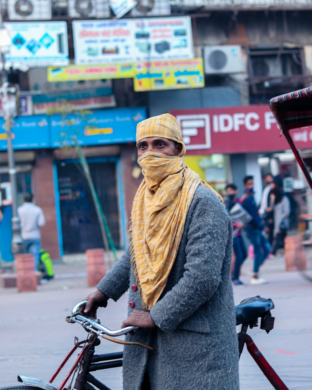 a man in a yellow scarf standing next to a bicycle