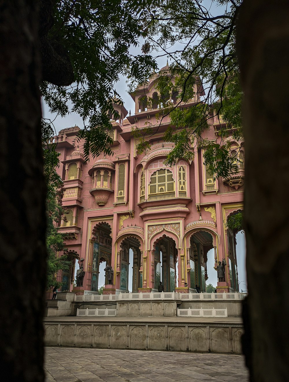 a large pink building sitting next to a tree