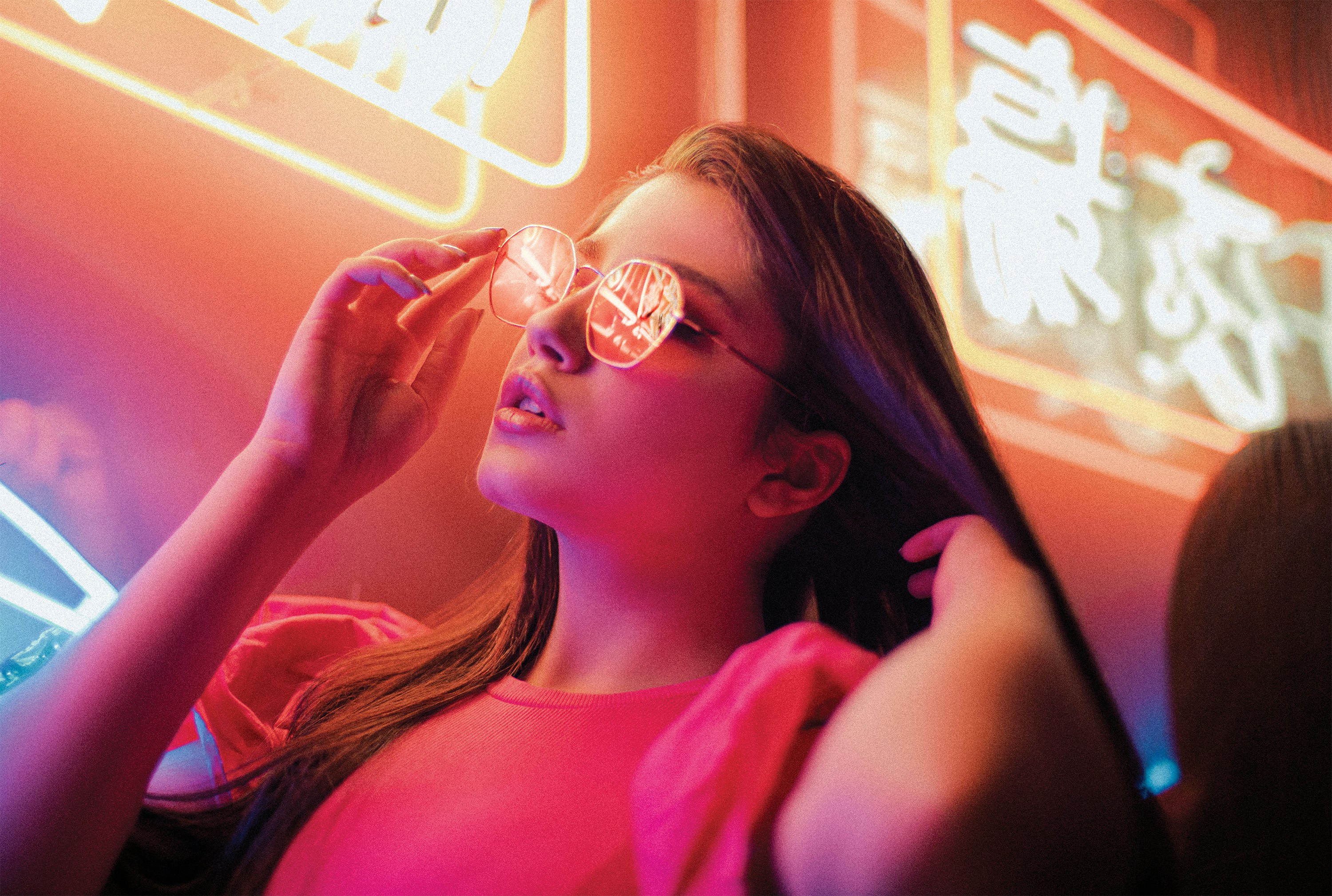 uma mulher em um top rosa está segurando um par de óculos