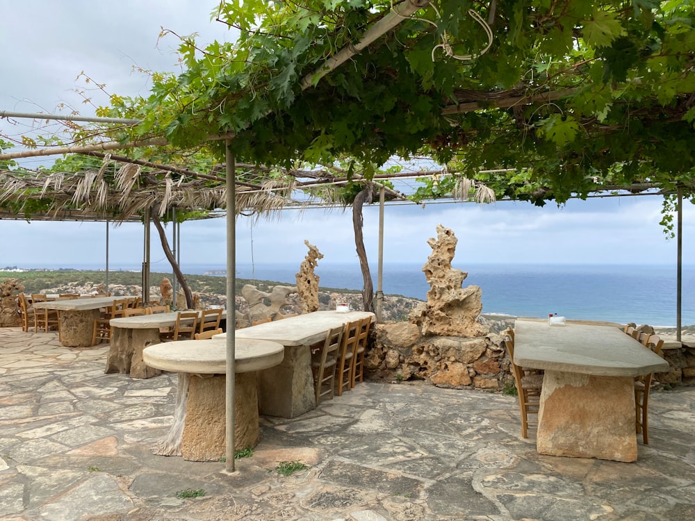 a stone table and benches under a pergolated roof