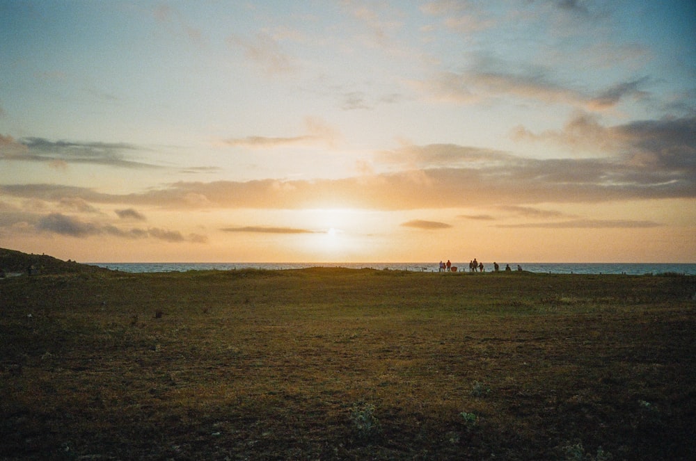 a group of people standing on top of a grass covered field