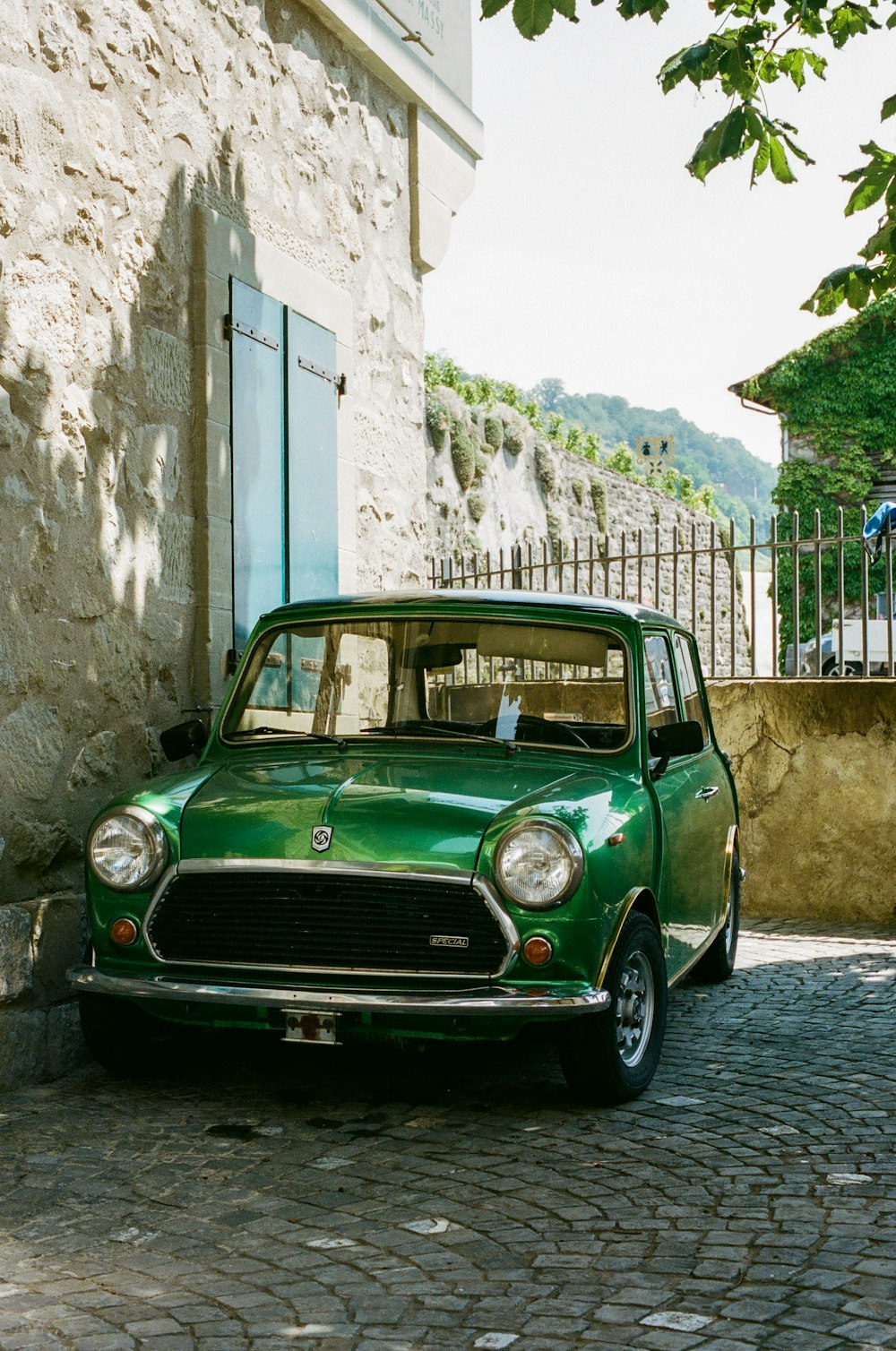 Ein kleines grünes Auto, das auf einer Kopfsteinpflasterstraße geparkt ist