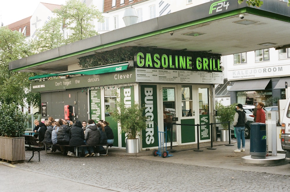 a group of people sitting outside of a gas station