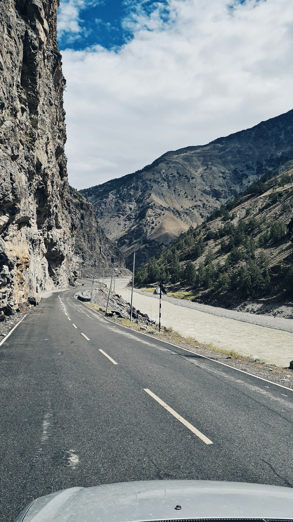 a car driving down a road next to a mountain