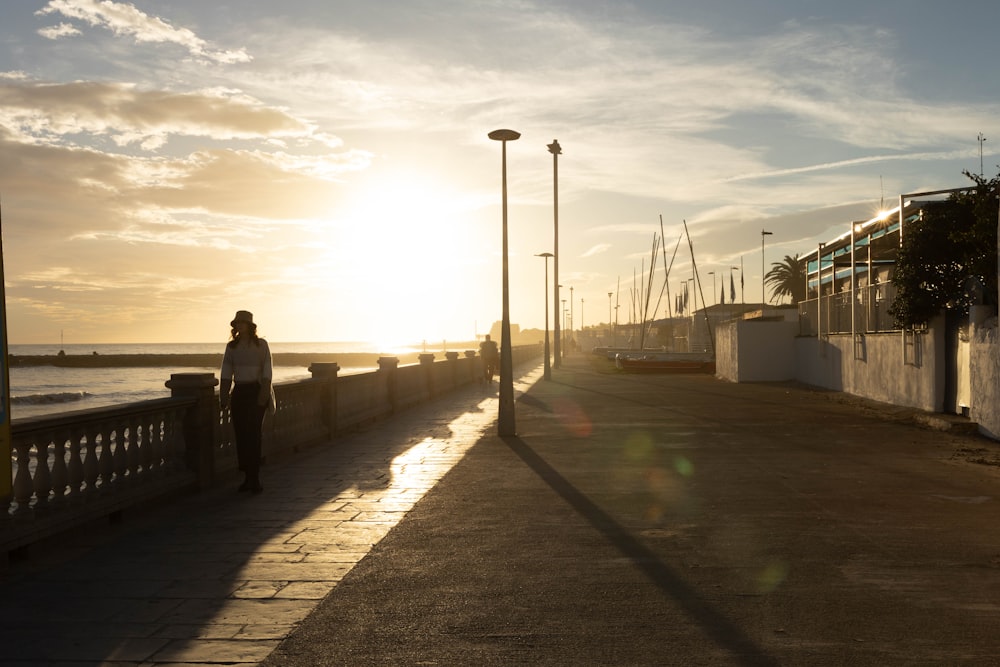 a person standing on a sidewalk next to the ocean