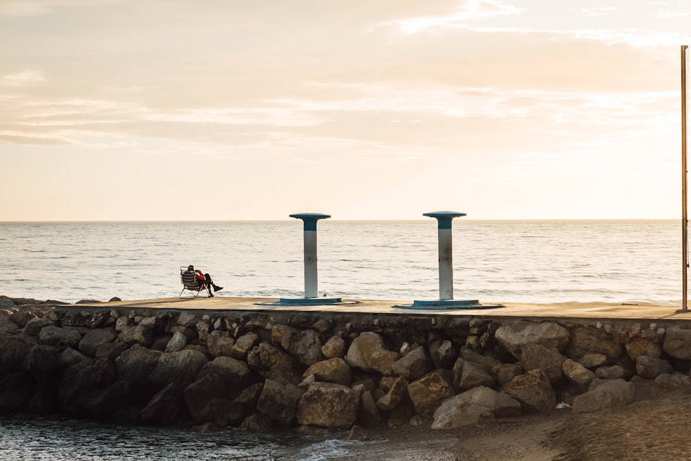 a person sitting on a bench near the ocean