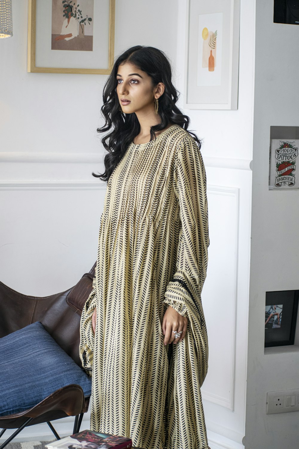 a woman standing in a living room next to a chair